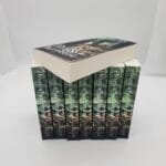 A stepped pyramid of hardcover books with dark green spines and vertical white text along the spines, stacked to form a blocky display.